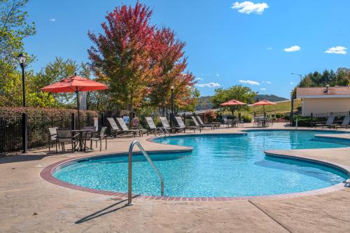 einen Pool mit Tischen, Stühlen und einem Sonnenschirm in der Unterkunft Club Wyndham Mountain Vista in Branson