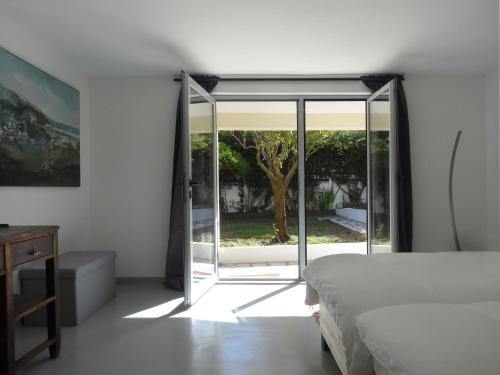 1 dormitorio con 1 cama y puerta corredera de cristal en Surf & Kite - Villa Nortada, en Charneca