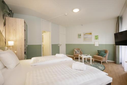 a hotel room with two beds and a tv at Hotel Het Heijderbos by Center Parcs in Heijen