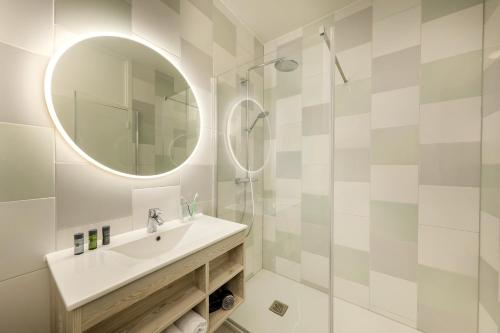 Baño blanco con lavabo y espejo en Hotel Het Heijderbos by Center Parcs, en Heijen