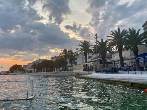 a boat in a body of water with palm trees at Apartments Grozdana in Gradac