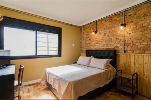 a bedroom with a bed and a brick wall at A CASINA - STUDIOS Metrô FARIA LIMA in São Paulo