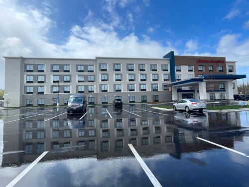 een groot gebouw met auto's geparkeerd op een parkeerplaats bij Hampton Inn & Suites Ypsilanti, MI in Ypsilanti