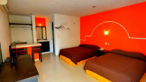 Habitación de hotel con 2 camas y paredes rojas en Hotel El Marques, en Mérida