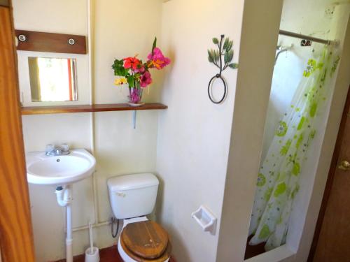 een badkamer met een toilet, een wastafel en bloemen bij La Familia Guest House and Natural Farm in Port Antonio