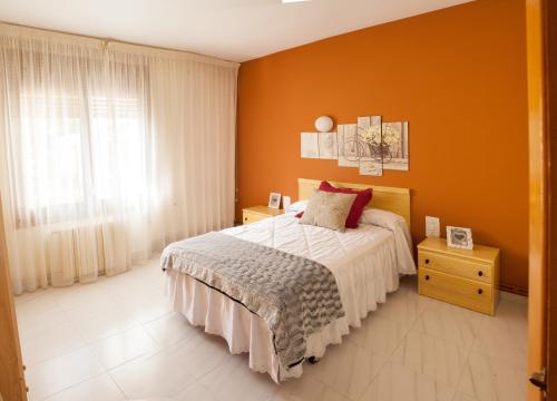 een slaapkamer met oranje muren en een bed en een raam bij Apartamentos rurales La posada de Donato in Nuévalos