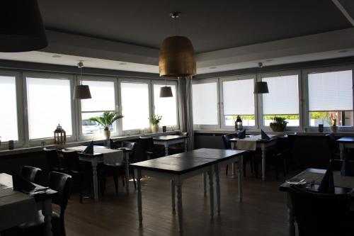 Un comedor con mesas y sillas y ventanas. en Gasthof Großer Krug, en Norddeich