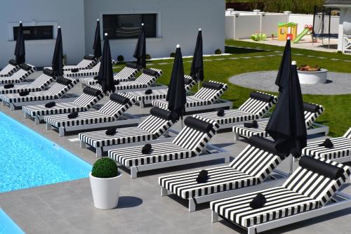 a group of lounge chairs with umbrellas next to a pool at Krystal Boutique Mansion in Hunedoara