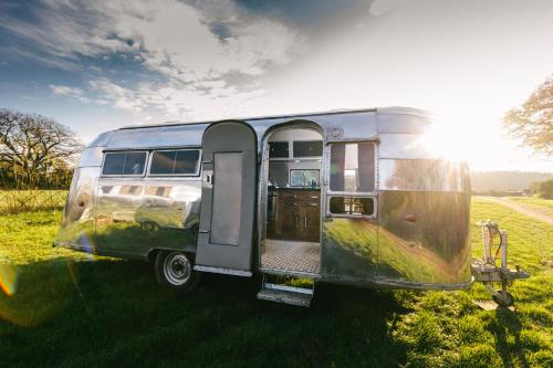 an old airstream trailer parked in a field at Silver Airstream Glamping & Rental in Chichester