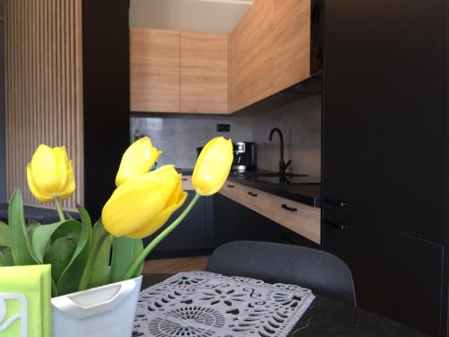 a kitchen with yellow tulips and a table in a kitchen at Apartament Malta Poznań in Poznań