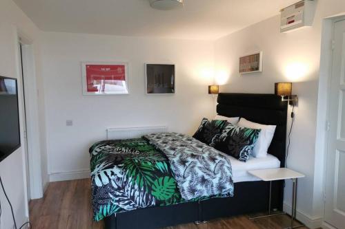 a bedroom with a bed with a green and white comforter at Stylish studio bungalow, close to Cardiff Centre in Cardiff