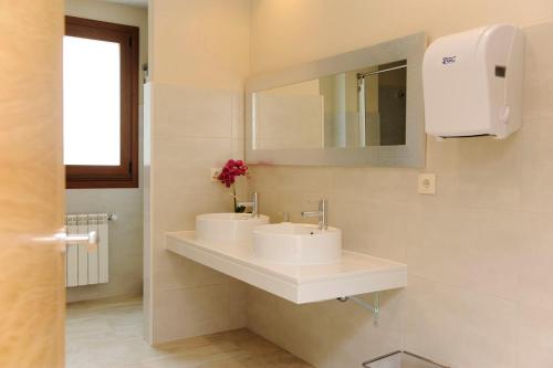 uma casa de banho com 2 lavatórios e um espelho em Albergue El Aleman em Boente