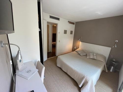 a small bedroom with a bed and a television at Hotel L'Orangeraie in Le Lavandou