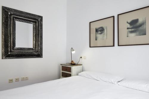 a white bedroom with two beds and a mirror at Idiakez - Basque Stay in San Sebastián