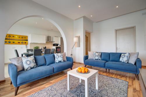 una sala de estar con sofás azules y una mesa. en Exceptional Tigne Seafront Apartments by Shortletsmalta, en Sliema