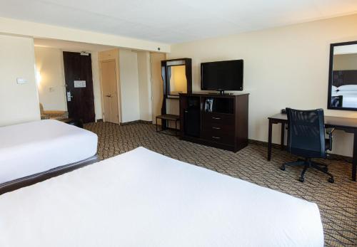 a hotel room with a bed and a desk with a television at Holiday Inn St. Louis Airport West Earth City by IHG in Earth City