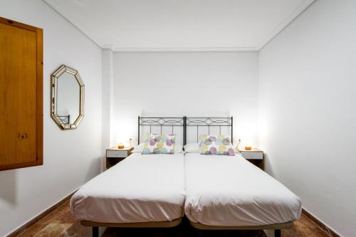 1 dormitorio con 1 cama blanca grande y espejo en Holi-Rent Estrella, en Sevilla