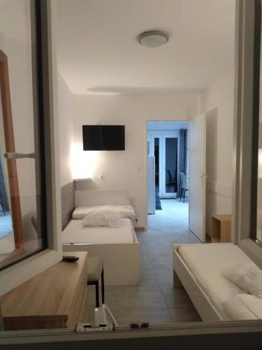 Cette chambre blanche comprend 2 lits et un miroir. dans l'établissement Les Asclepiades, à Argelès-sur-Mer