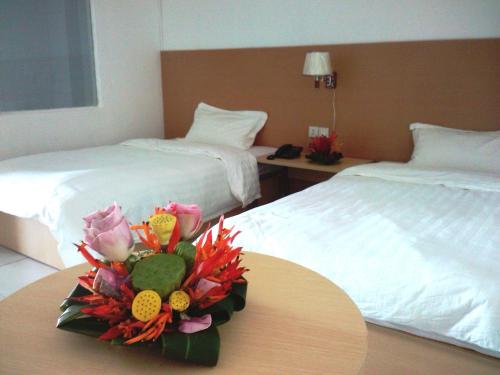 um quarto de hotel com duas camas e uma mesa com flores em Airlines Business Hotel em Port Vila