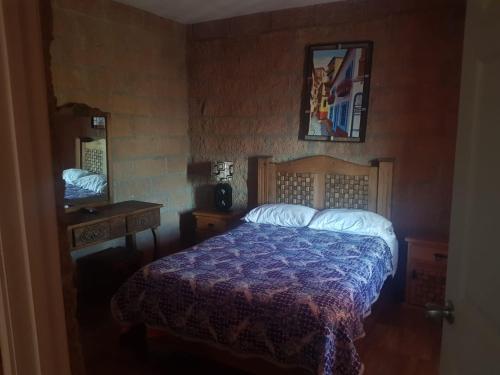 a bedroom with a bed with a purple comforter and a mirror at Hotel La Cabaña in San Miguel de Allende