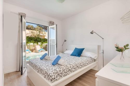 a white bedroom with a bed with blue pillows at Villa Pins Ciutadella by Villa Plus in Cala Blanca