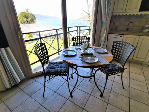una mesa y sillas en una cocina con vistas al océano en Lac Annecy plage privée, Duplex Baie des voiles, en Duingt