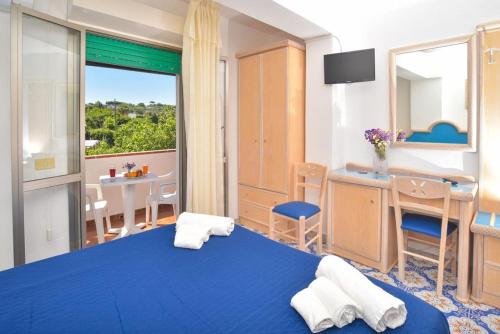 a bedroom with a blue bed and a desk and a table at Hotel Villa Cimmentorosso in Ischia