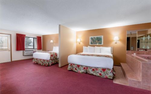 a hotel room with two beds and a bathtub at Aloha Beach Resort in Wisconsin Dells