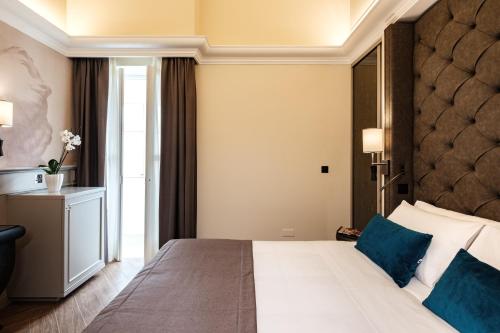 a bedroom with a large white bed with blue pillows at Hotel Pjazza Merkanti - Boutique Living in Valletta