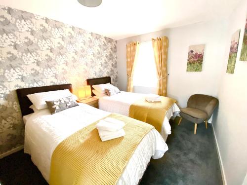 una habitación de hotel con 2 camas y una silla en Cosy, Modern 2 Bedroom Apartment in the Centre of Inveraray, en Inveraray