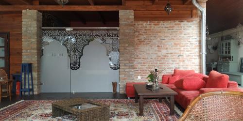 a living room with a red couch and a brick wall at Guest House Romantika Panzio in Gyula