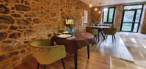 a dining room with two tables and a stone wall at Ecocasa Lema II in Muxia