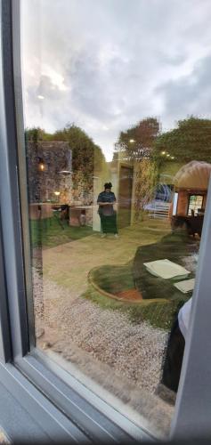 a window with a man sitting in a chair in a yard at Ecocasa Lema II in Muxia