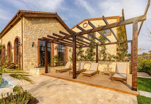 an outdoor patio with chairs and a wooden pergola at Bengodi Boutique Hotel in Eceabat