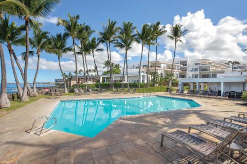 una piscina con sedie e palme di Wyndham Royal Sea Cliff Resort a Kailua-Kona