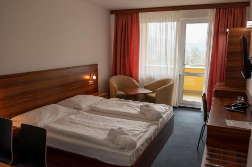 ein Hotelzimmer mit einem Bett, einem Schreibtisch und einem Fenster in der Unterkunft Lipno Wellness - Frymburk C 402-403 in Frymburk