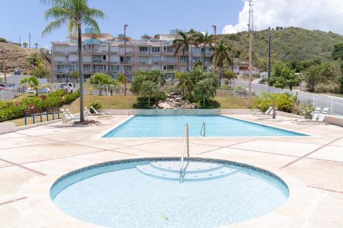 una piscina en un patio con un edificio al fondo en Apartment in Villas Del Faro Resort with WIFI en Maunabo