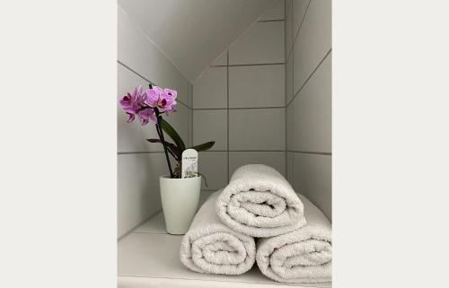 a bathroom with two towels and a vase with flowers at Andrea Apartmanok in Hajdúszoboszló
