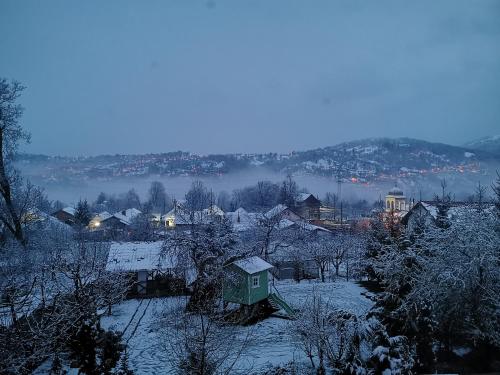 a village covered in snow with a house in the foreground at Casa Bunicii Comarnic in Comarnic