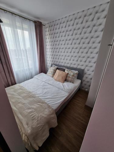 a small bed in a room with a window at Kawalerka blisko jeziora in Olecko