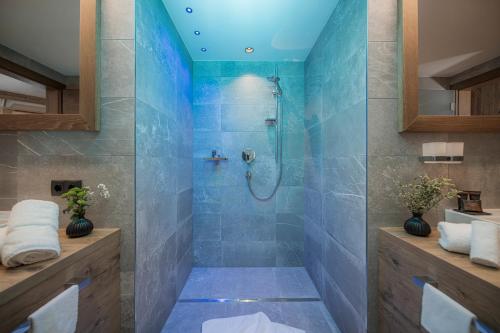 a bathroom with a shower with blue tiles at Aparthotel Stacherhof in Fügen