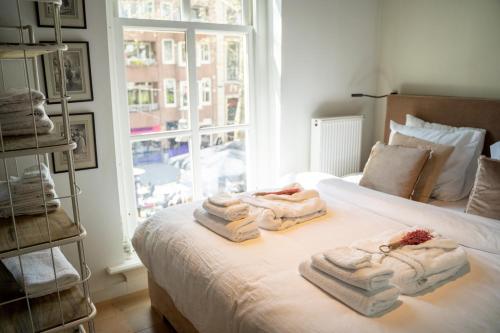 a bedroom with towels on a bed with a window at Ginny's studio op de Grote Markt in Breda