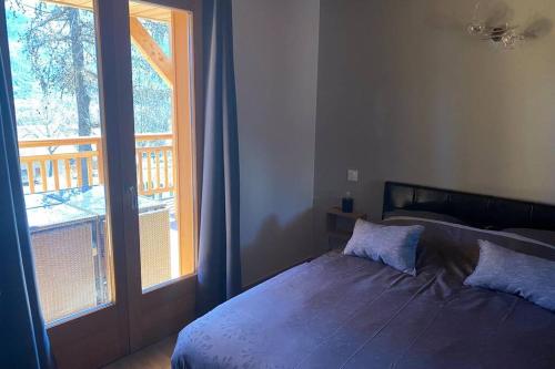 a bedroom with a bed and a large window at Charmant logement à Serre Chevalier in Puy-Saint-Pierre
