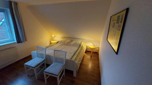 a small bedroom with a bed and two chairs at Finkennest Wolke 7 in Carolinensiel