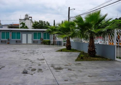 a building with two palm trees in a parking lot at Hotel Las Vegas in Poza Rica de Hidalgo