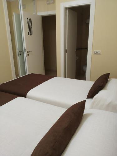 a bedroom with two beds with brown pillows at Hostal Stella Del Mare in Camariñas