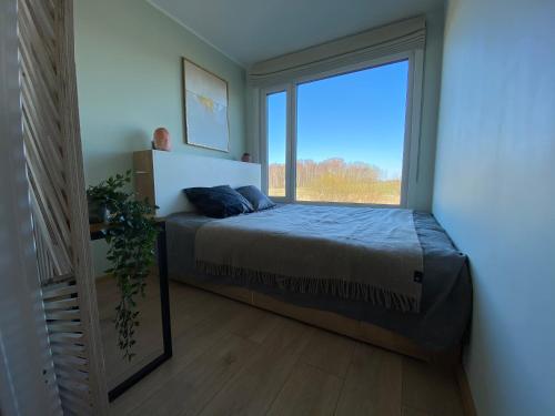 a bedroom with a bed and a large window at Cozy house with sauna by the lake in Lokuti