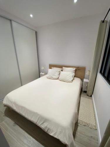 1 dormitorio con 1 cama blanca con sábanas y almohadas blancas en Ajaccio Magnifique T2 45m2 neuf 5 personnes Clim wifi stationnement gratuit centre ville plage à 300m, en Ajaccio
