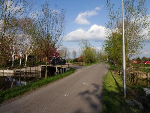 a road next to a river with a bridge at De Kopstoof in Lekkerkerk