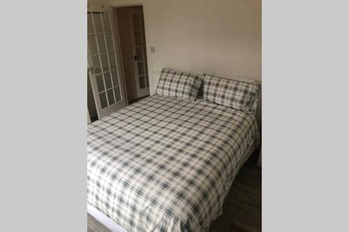 a bed in a room with a checkered blanket at One bedroom Flat on the banks of Loch Lomond in Alexandria